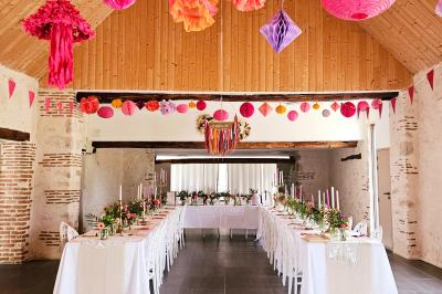 Bouquet de fleurs blanches et vertes au premier plan, avec des chaises disposées en extérieur sous un grand arbre.
