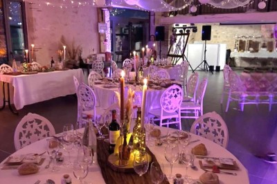 Bouquet de fleurs blanches et vertes au premier plan, avec des chaises disposées en extérieur sous un grand arbre.