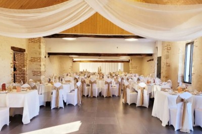 Bouquet de fleurs blanches et vertes au premier plan, avec des chaises disposées en extérieur sous un grand arbre.