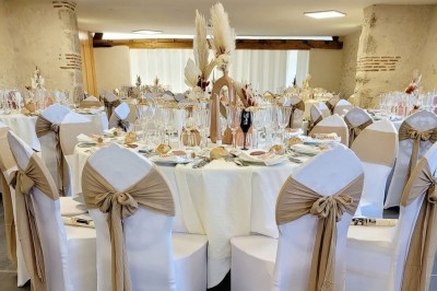 Bouquet de fleurs blanches et vertes au premier plan, avec des chaises disposées en extérieur sous un grand arbre.