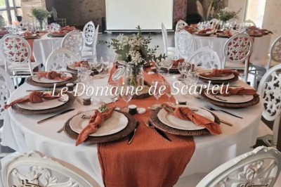 Bouquet de fleurs blanches et vertes au premier plan, avec des chaises disposées en extérieur sous un grand arbre.