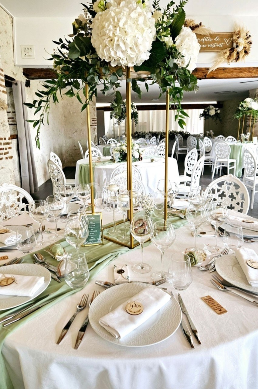 Table de réception élégamment dressée avec nappes blanches, décorations florales et vaisselle raffinée dans une salle…