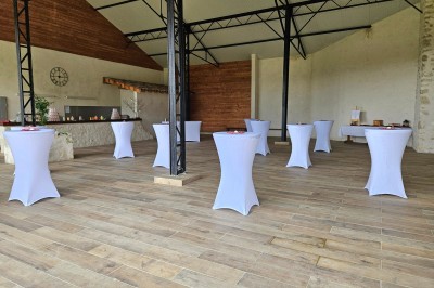 Un couple en tenue de mariage s'embrasse devant une arche décorée, dans un cadre champêtre en plein air.