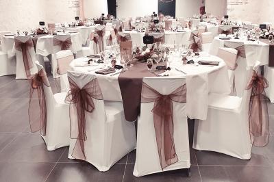 Bouquet de fleurs blanches et vertes au premier plan, avec des chaises disposées en extérieur sous un grand arbre.