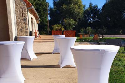 Bouquet de fleurs blanches et vertes au premier plan, avec des chaises disposées en extérieur sous un grand arbre.