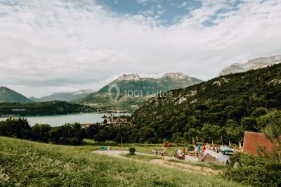 Terrasse extérieure animée avec tables, guirlandes lumineuses, vue sur un lac et montagnes en arrière-plan.