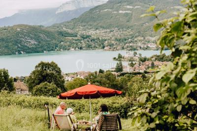 Terrasse extérieure animée avec tables, guirlandes lumineuses, vue sur un lac et montagnes en arrière-plan.