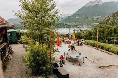 Terrasse extérieure animée avec tables, guirlandes lumineuses, vue sur un lac et montagnes en arrière-plan.