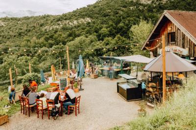 Terrasse extérieure animée avec tables, guirlandes lumineuses, vue sur un lac et montagnes en arrière-plan.