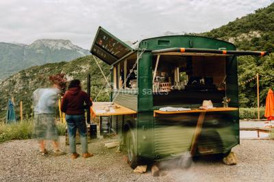 Terrasse extérieure animée avec tables, guirlandes lumineuses, vue sur un lac et montagnes en arrière-plan.