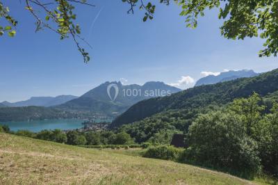 Vue nocturne d'un paysage montagneux avec un village éclairé au loin et une terrasse illuminée au premier plan.