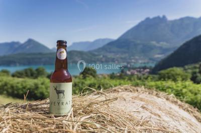 Vue nocturne d'un paysage montagneux avec un village éclairé au loin et une terrasse illuminée au premier plan.