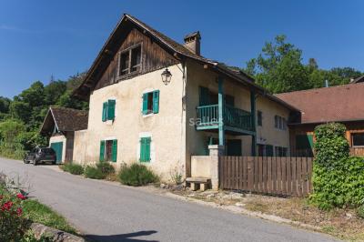 Vue nocturne d'un paysage montagneux avec un village éclairé au loin et une terrasse illuminée au premier plan.