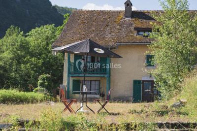 Vue nocturne d'un paysage montagneux avec un village éclairé au loin et une terrasse illuminée au premier plan.