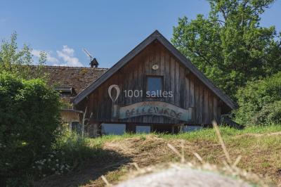 Vue nocturne d'un paysage montagneux avec un village éclairé au loin et une terrasse illuminée au premier plan.