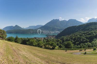 Vue nocturne d'un paysage montagneux avec un village éclairé au loin et une terrasse illuminée au premier plan.