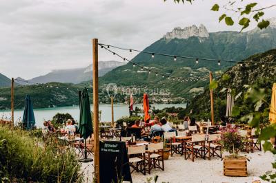 Vue nocturne d'un paysage montagneux avec un village éclairé au loin et une terrasse illuminée au premier plan.