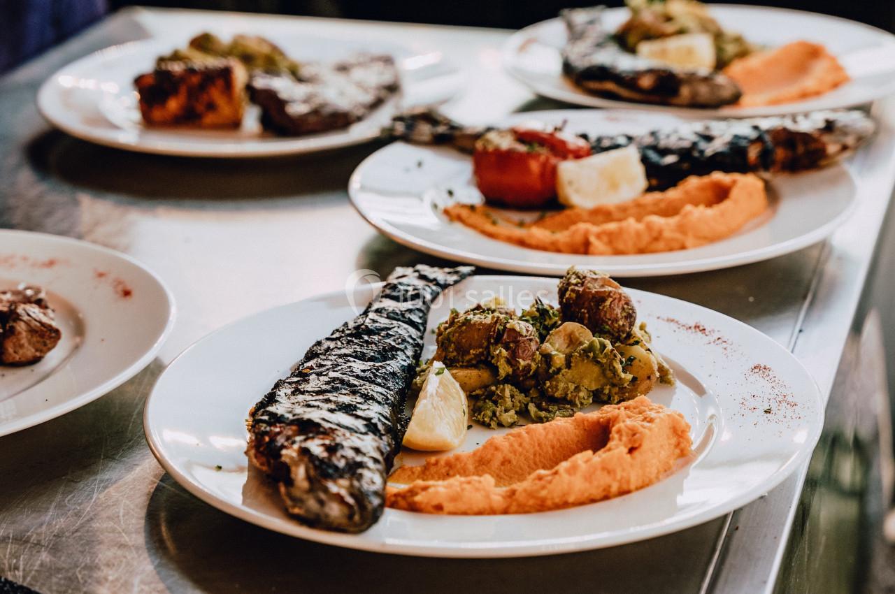 Assiettes de poisson grillé accompagnées de purée et légumes, servies sur une table en métal.