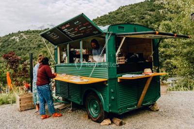 Vue nocturne d'un paysage montagneux avec un village éclairé au loin et une terrasse illuminée au premier plan.