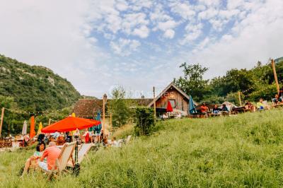 Vue nocturne d'un paysage montagneux avec un village éclairé au loin et une terrasse illuminée au premier plan.