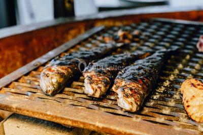 Vue nocturne d'un paysage montagneux avec un village éclairé au loin et une terrasse illuminée au premier plan.
