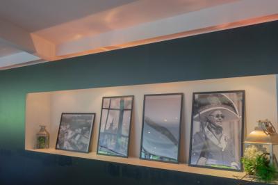 Salon avec fauteuils en cuir, table basse en bois, plante verte, bibliothèque et tableau sur un mur lambrissé.