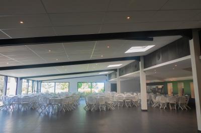 Salon avec fauteuils en cuir, table basse en bois, plante verte, bibliothèque et tableau sur un mur lambrissé.