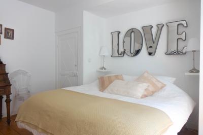 Salon avec fauteuils en cuir, table basse en bois, plante verte, bibliothèque et tableau sur un mur lambrissé.