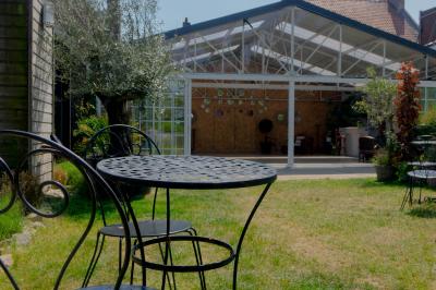 Salon avec fauteuils en cuir, table basse en bois, plante verte, bibliothèque et tableau sur un mur lambrissé.
