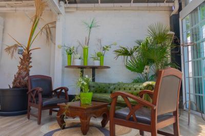 Salon avec fauteuils en cuir, table basse en bois, plante verte, bibliothèque et tableau sur un mur lambrissé.