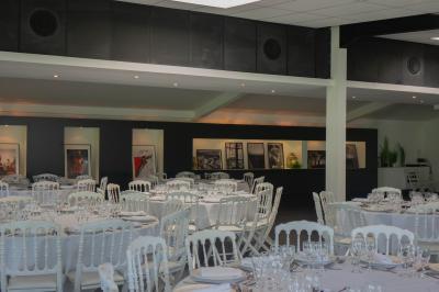 Salon avec fauteuils en cuir, table basse en bois, plante verte, bibliothèque et tableau sur un mur lambrissé.