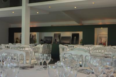Salon avec fauteuils en cuir, table basse en bois, plante verte, bibliothèque et tableau sur un mur lambrissé.