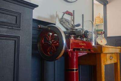Salon avec fauteuils en cuir, table basse en bois, plante verte, bibliothèque et tableau sur un mur lambrissé.