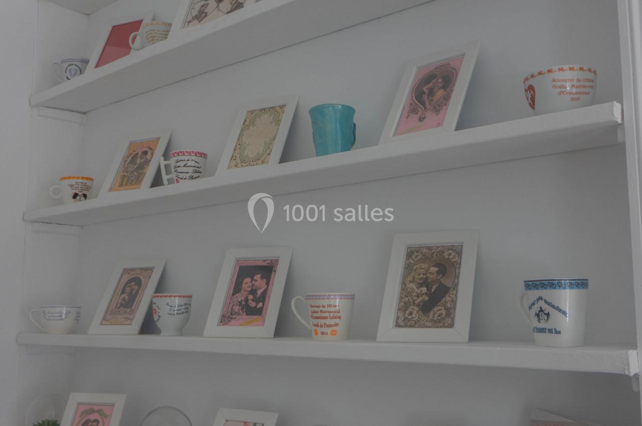 Étagères blanches décorées de cadres, tasses colorées, plantes et magazines sur un meuble en bois.