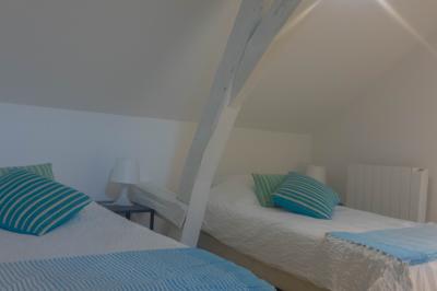 Salon avec fauteuils en cuir, table basse en bois, plante verte, bibliothèque et tableau sur un mur lambrissé.