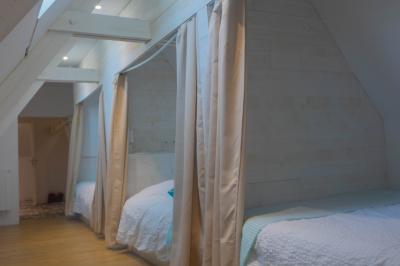 Salon avec fauteuils en cuir, table basse en bois, plante verte, bibliothèque et tableau sur un mur lambrissé.