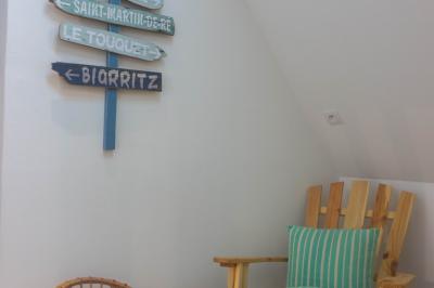 Salon avec fauteuils en cuir, table basse en bois, plante verte, bibliothèque et tableau sur un mur lambrissé.