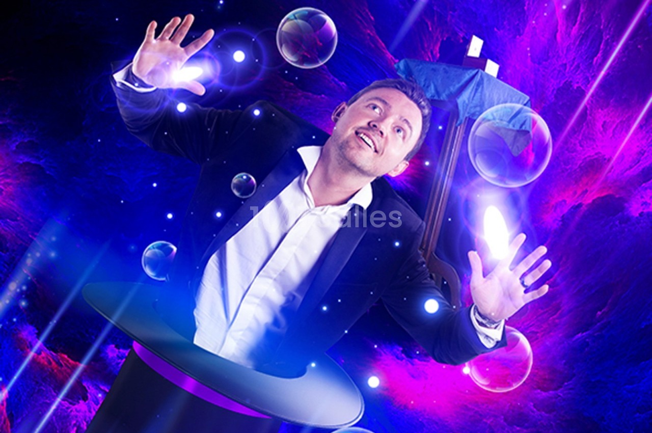 Un homme en costume semble émerger d'un chapeau magique, entouré de bulles et d'effets lumineux violets.