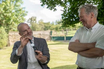 Un groupe de personnes assises et debout, riant et échangeant lors d'un moment convivial en extérieur.
