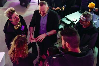 Un groupe de personnes assises et debout, riant et échangeant lors d'un moment convivial en extérieur.