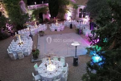 Vue aérienne d'un bâtiment historique entouré de jardins, de vignes et de maisons dans un paysage rural.