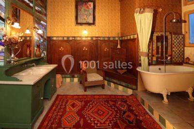 Vue aérienne d'un bâtiment historique entouré de jardins, de vignes et de maisons dans un paysage rural.