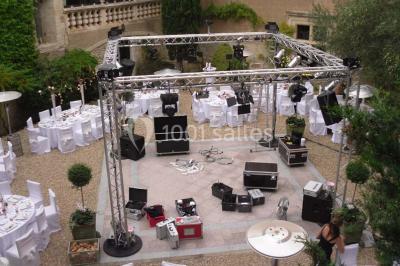 Vue aérienne d'un bâtiment historique entouré de jardins, de vignes et de maisons dans un paysage rural.