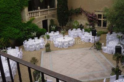 Vue aérienne d'un bâtiment historique entouré de jardins, de vignes et de maisons dans un paysage rural.