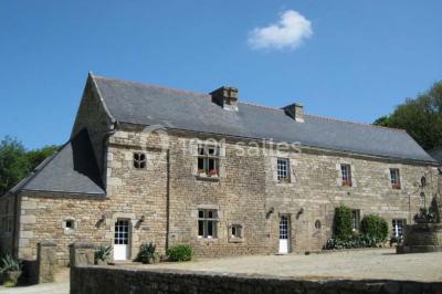 Piscine intérieure visible à travers une baie vitrée entourée de murs recouverts de plantes grimpantes, avec des tables…