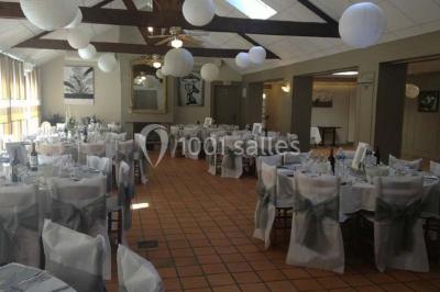 Piscine intérieure visible à travers une baie vitrée entourée de murs recouverts de plantes grimpantes, avec des tables…