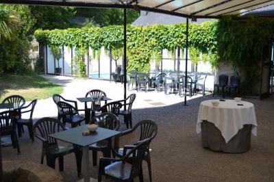Piscine intérieure visible à travers une baie vitrée entourée de murs recouverts de plantes grimpantes, avec des tables…