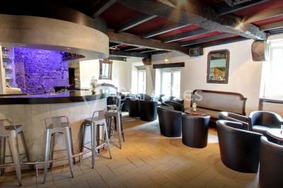 Piscine intérieure visible à travers une baie vitrée entourée de murs recouverts de plantes grimpantes, avec des tables…