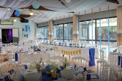 Piscine intérieure visible à travers une baie vitrée entourée de murs recouverts de plantes grimpantes, avec des tables…