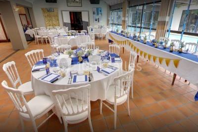 Piscine intérieure visible à travers une baie vitrée entourée de murs recouverts de plantes grimpantes, avec des tables…